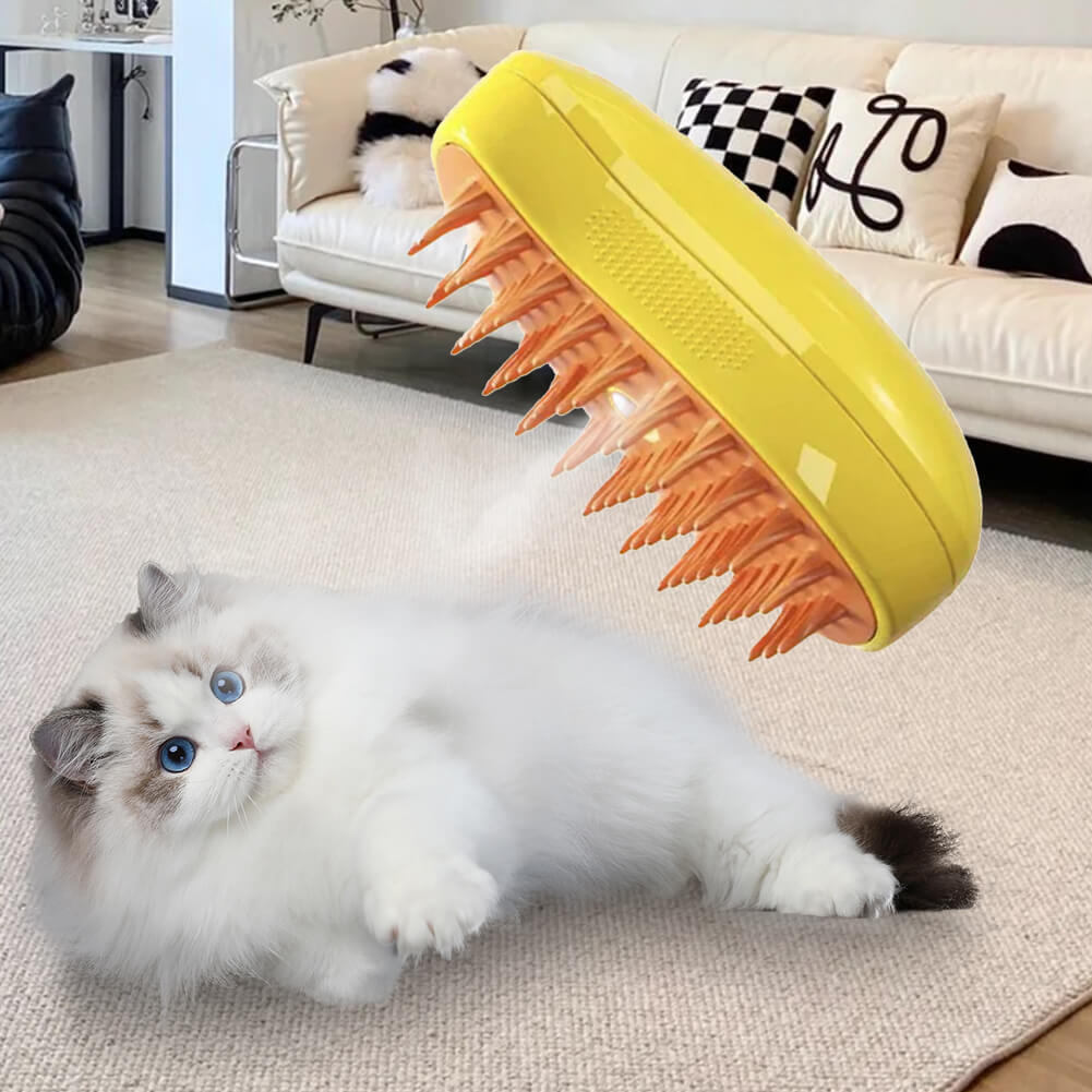 Depicted is a plastic cat brush with a unique design: the top part is a vibrant yellow, while the bristles are crafted from a soft, silicone material in a bright orange hue. A key feature of the brush is a hole in the middle, from which steam is visibly emanating, adding a distinctive functionality to this grooming tool. In the background, a white cat is lying down contentedly on a carpet in the living room, enhancing the domestic and cozy setting of the scene.